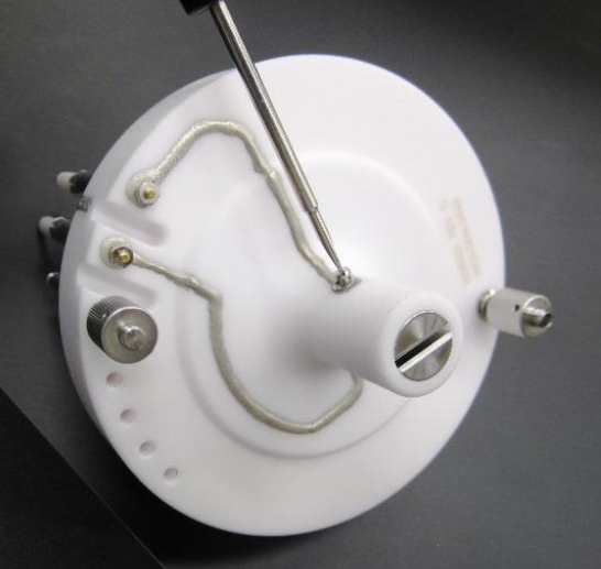 A white round object with a screwdriver  Description automatically generated
